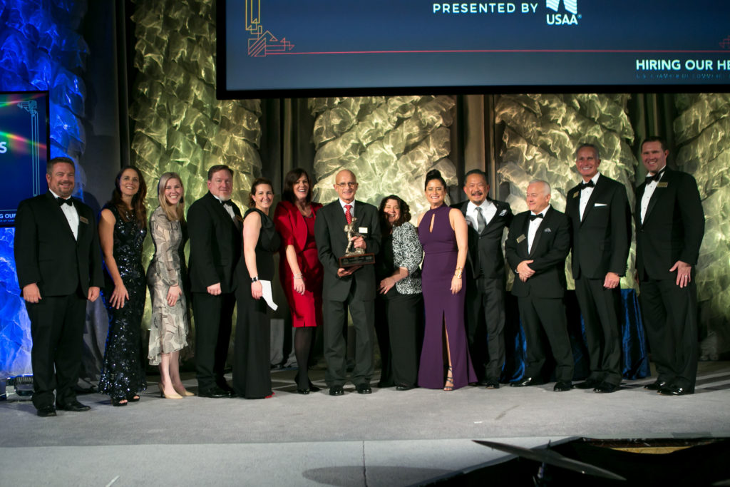 Group of men and women pose for a photo smiling while accepting the 2018 USAA Military Spouse Employment and Mentoring Award.