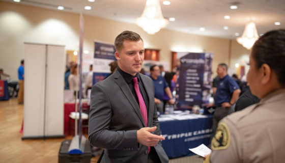 a man in a suit and tie talks to an employer at a job fair