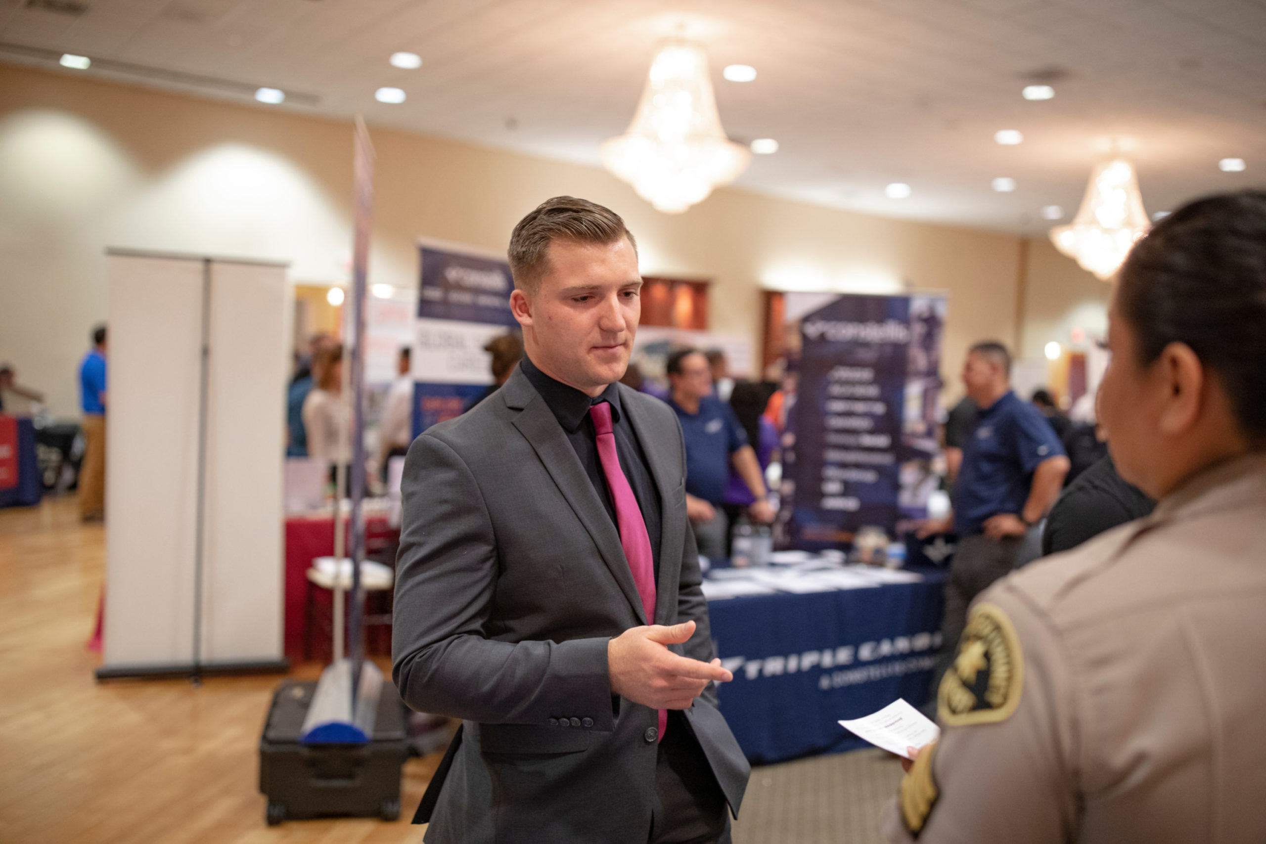 a man in a suit and tie talks to an employer at a job fair