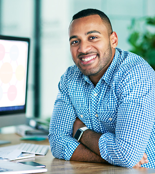 Career Forward man smiling at a desk near his computer