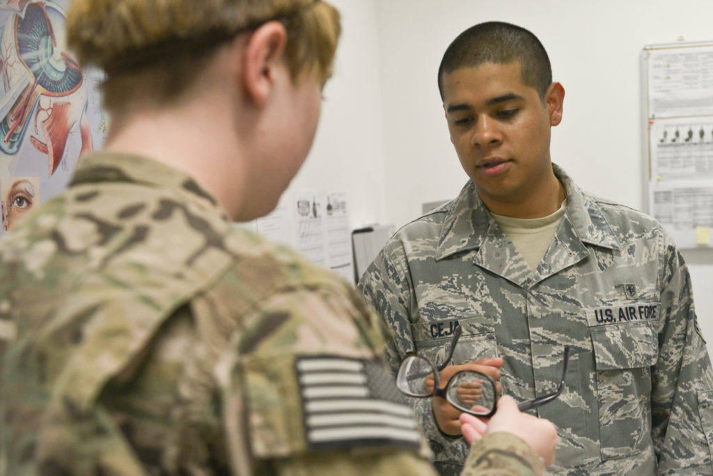 An Air Force airman helps a soldier adjust her glasses.