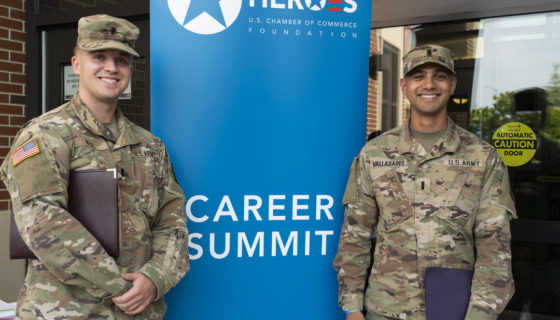 Two Army soldiers stand in front of Hiring Our Heroes Career Summit sign