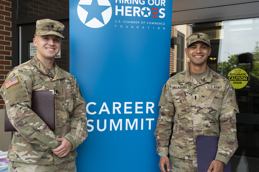 Two Army soldiers stand in front of Hiring Our Heroes Career Summit sign