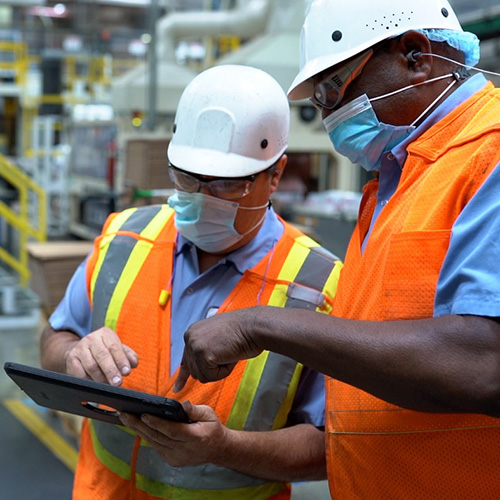 Veterans working at Nestle USA wearing safety gear discussing work over a tablet