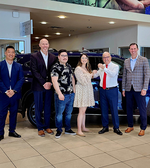 2022 Toyota Sweepstakes winner Andrew Unzueta holding keys to a new Toyota, stands with her spouse and other representatives.