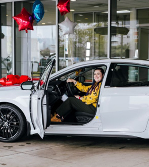 U.S. Air Force veteran Christina Sheets sits in a 2024 Toyota Camry XSE thanks to Toyota and Hiring Our Heroes Committed to America's Heroes Sweepstakes