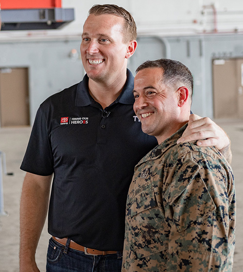 Dakota Meyer poses for a photo, smiling with a service member.