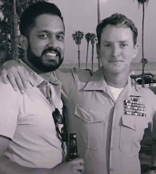 Screenshot from a YouTube video showing a uniformed Brian Hutcherson, former corporate fellow with Hiring Our Heroes, with his arm around a friend in front of palm trees in San Diego.