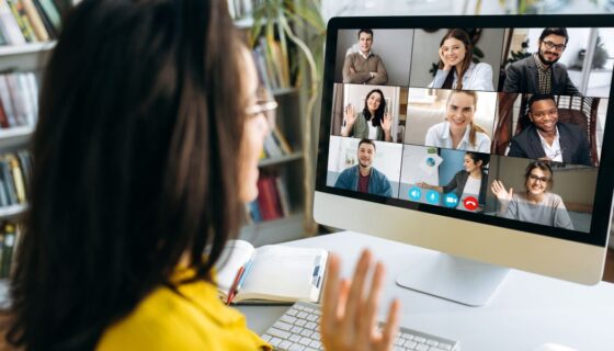 Virtual interview being conducted for a woman in yellow on a computer screen with nine people.