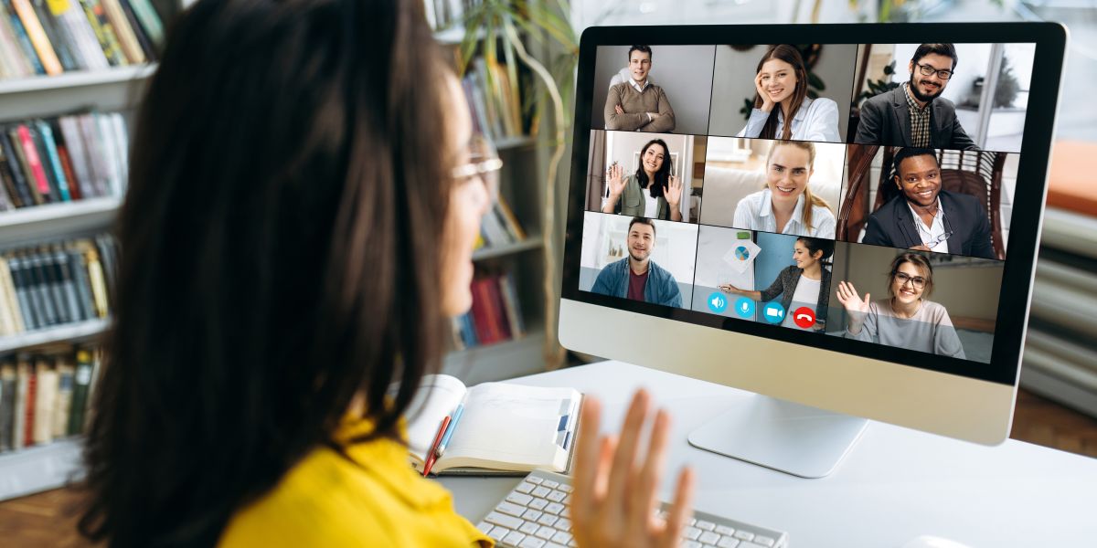 Virtual interview being conducted for a woman in yellow on a computer screen with nine people.