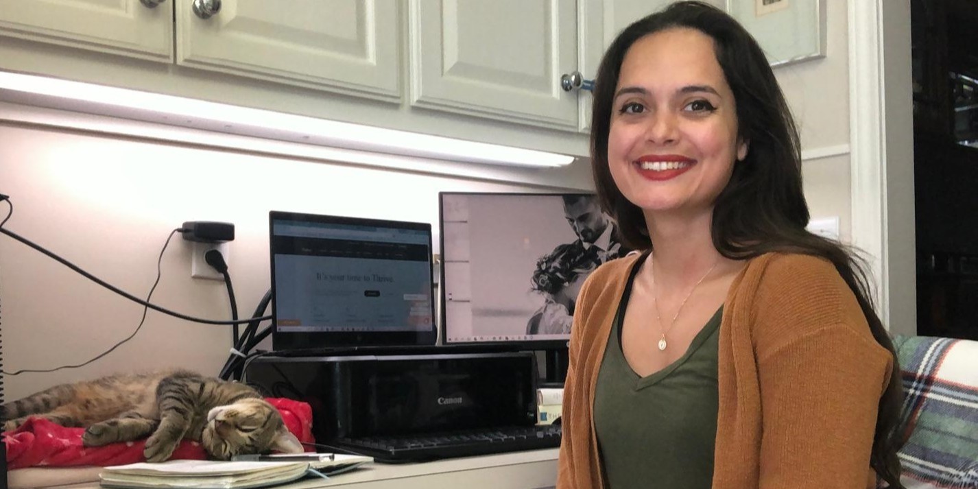 Karen Uhlhorn sitting at her remote workstation in her house with her trusty co-worker (and cat) – Petrus.