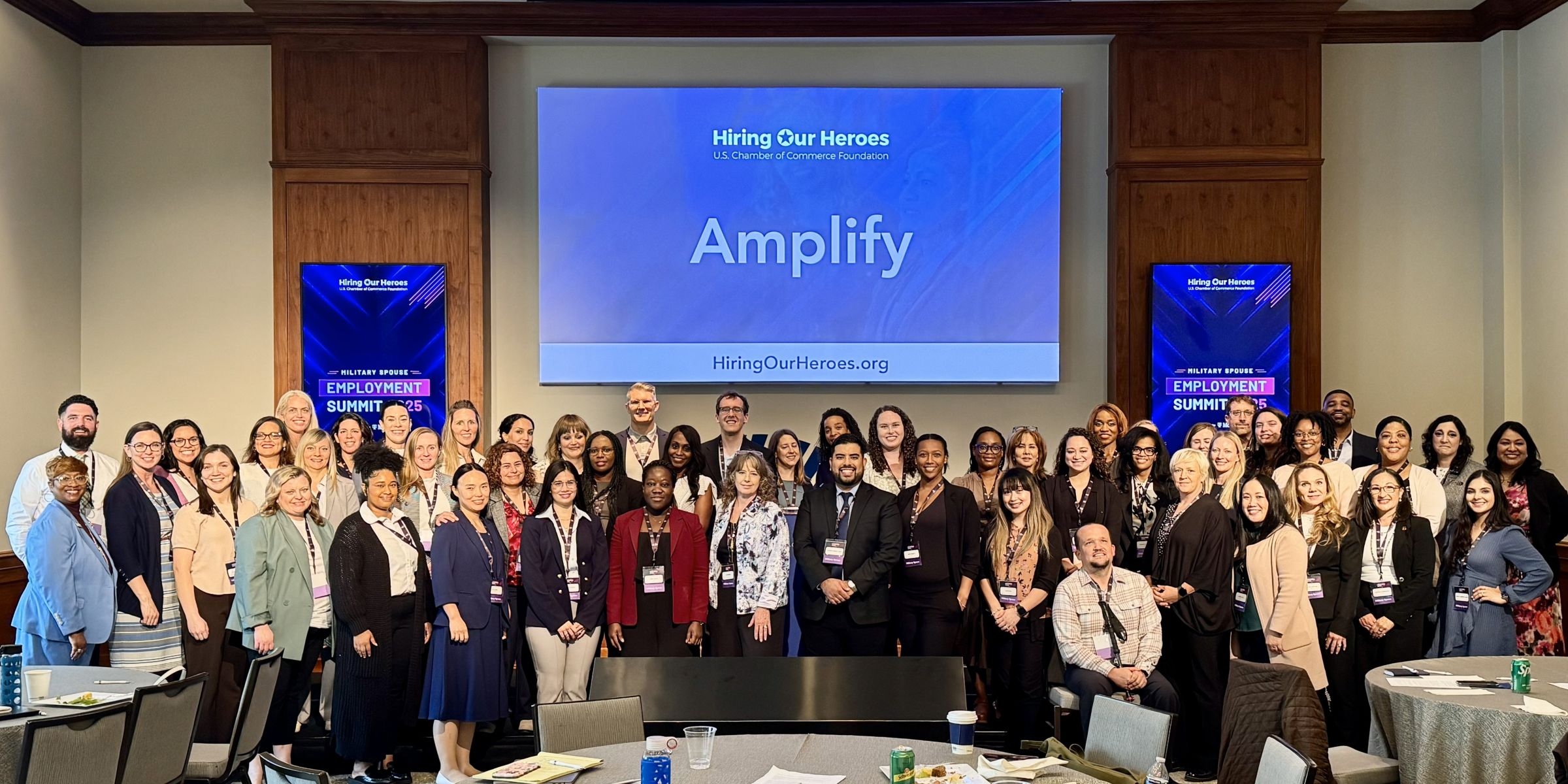 Some of the Amplify 2025 participants pose in front of Amplify screen.
