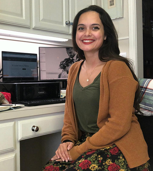 Military spouse Karen Ulhorn smiles, sitting in her home workspace.