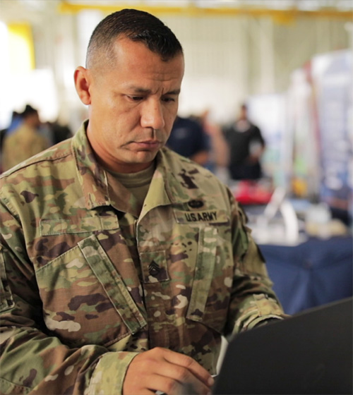 service member in uniform works on a laptop