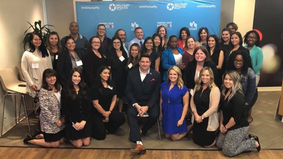 Amplify attendees pose for a photo in front of an Amplify backdrop during an event at Microsoft in San Diego in 2018.