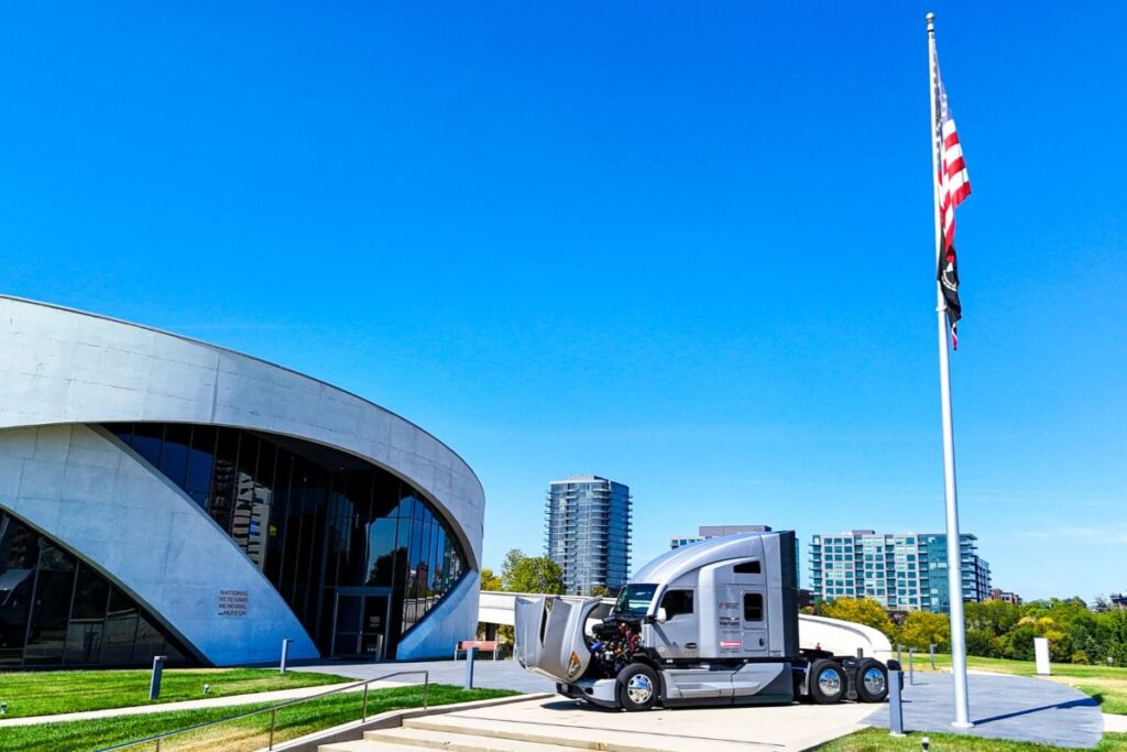 Image of brand new Kensworth truck with American flag and building