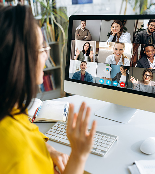 female professional sitting at a desk on a virtual call with other team members.