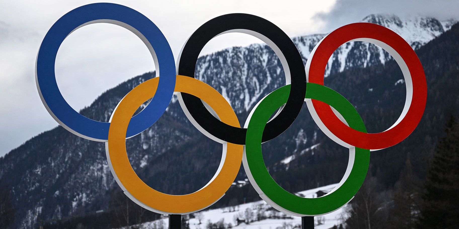 The Olympic rings in front of a snowy mountain in Italy.