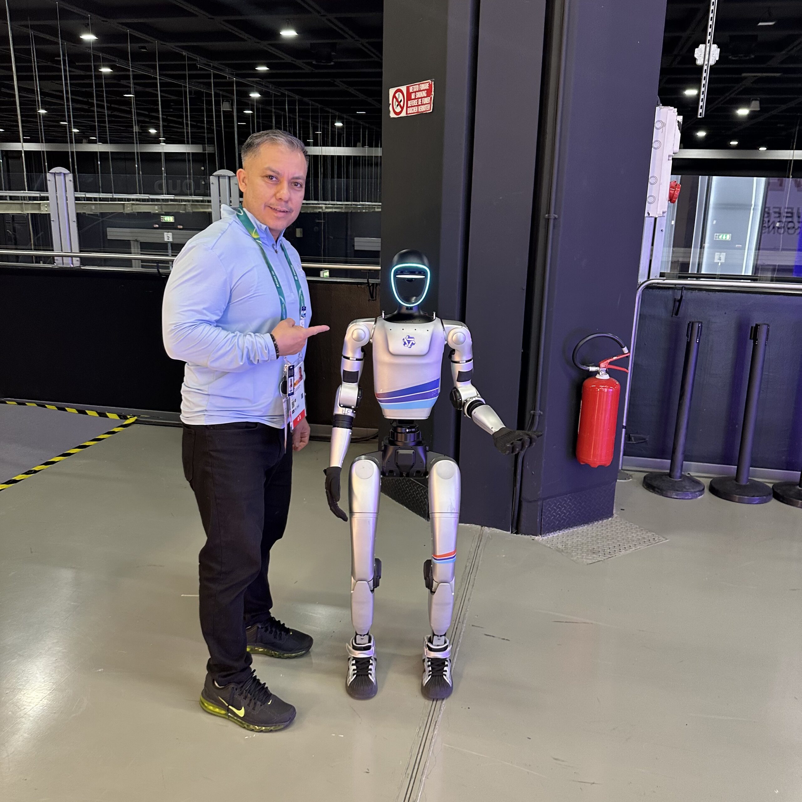 Anuar Pinto Velasco poses next to a humanoid robot at the 2026 Winter Olympics.