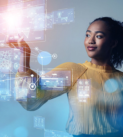 Young woman wearing holds her hand up to digital renderings on a transparent screen.