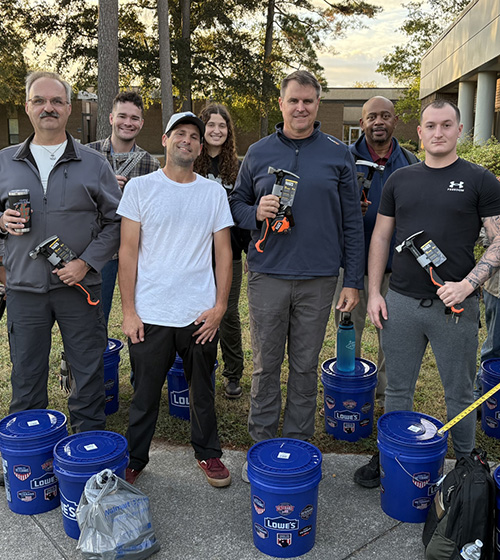 Men and women in the Skill Trades Academy smile with tools provided by Lowe's.