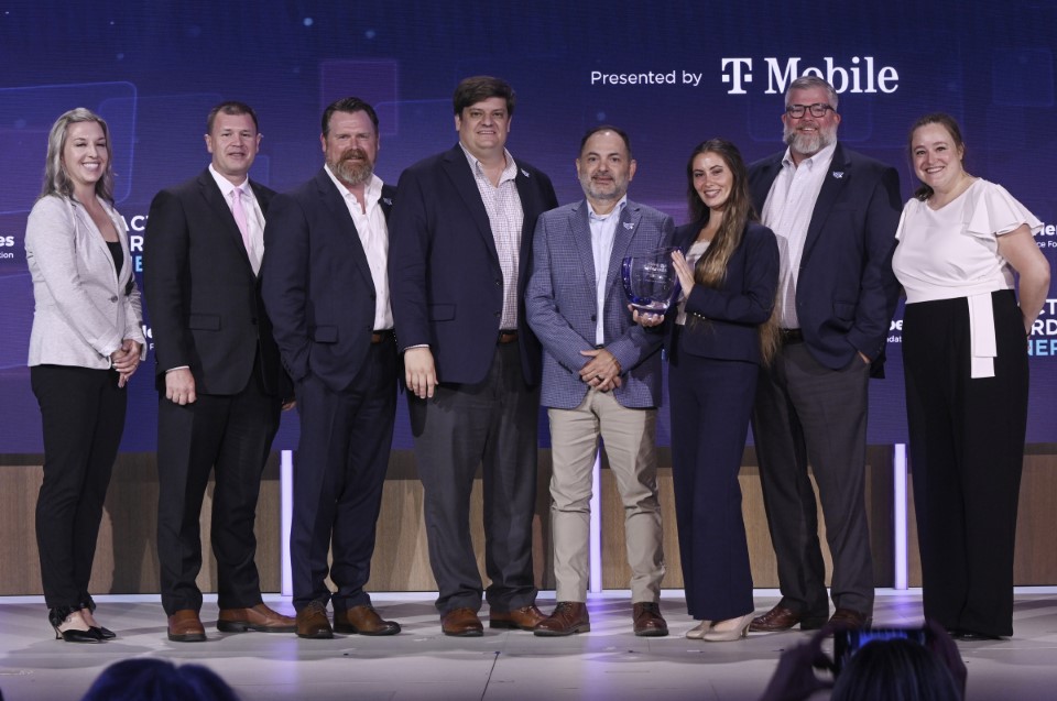 Eight people pose with the Community Leader Impact Award presented to the State of Louisiana and The Boot. 