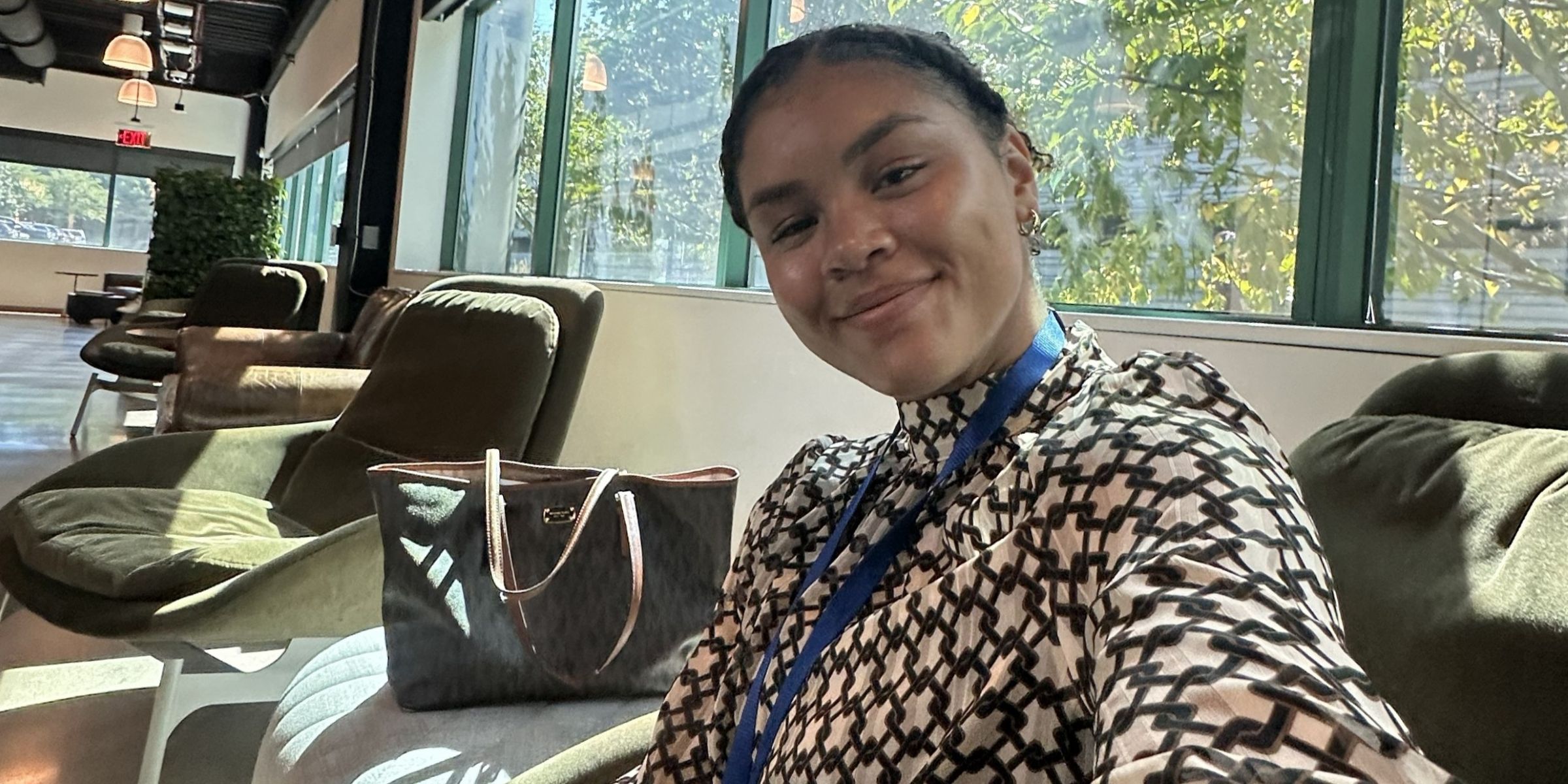 Lyric Green in professional attire sitting in an office building reception area.