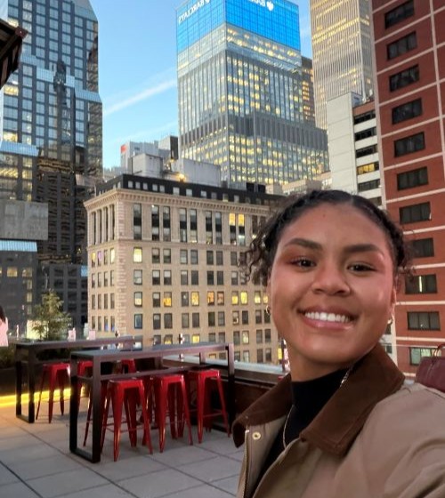 Lyric Green on a rooftop overlooking a skyline with tall buildings.