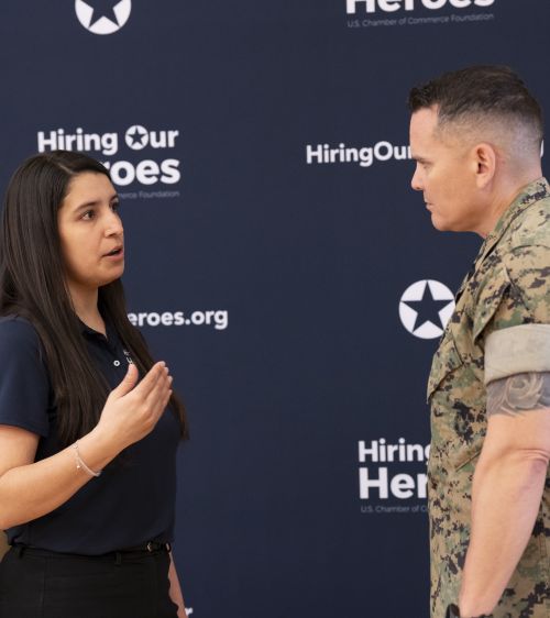 Female career connector from Hiring Our Heroes speaks with a man in uniform