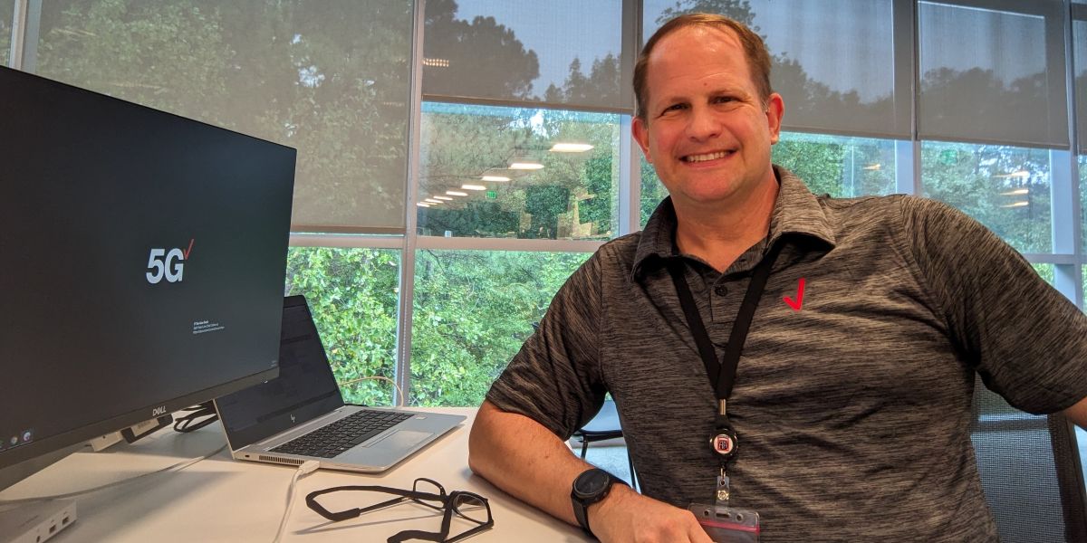 Marc Gaguzis sits at his desk with his Verizon computer.