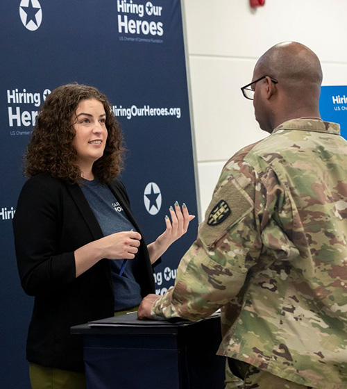 A female Hiring Our Heroes Career Connector speaks with a service member in uniform.