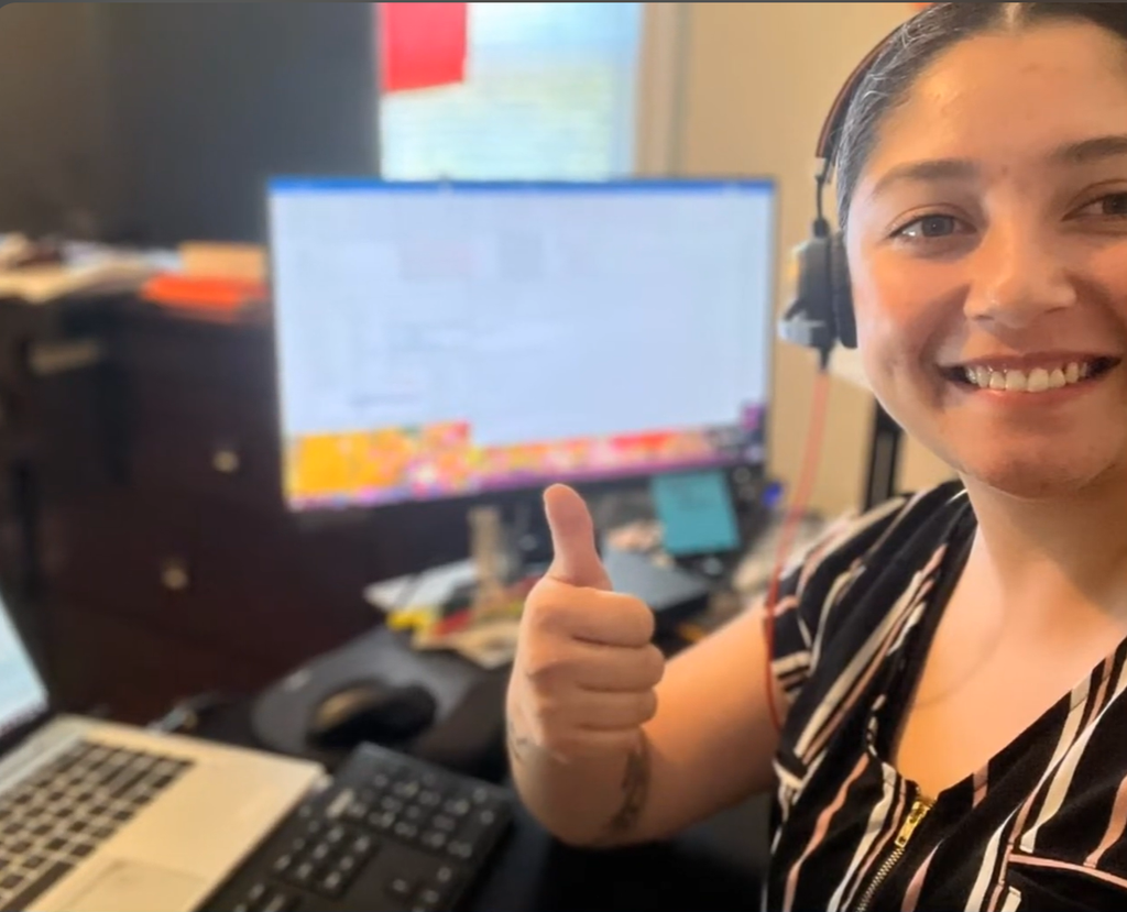 A woman giving a thumbs up in front of her computer for a cohort in 2022.