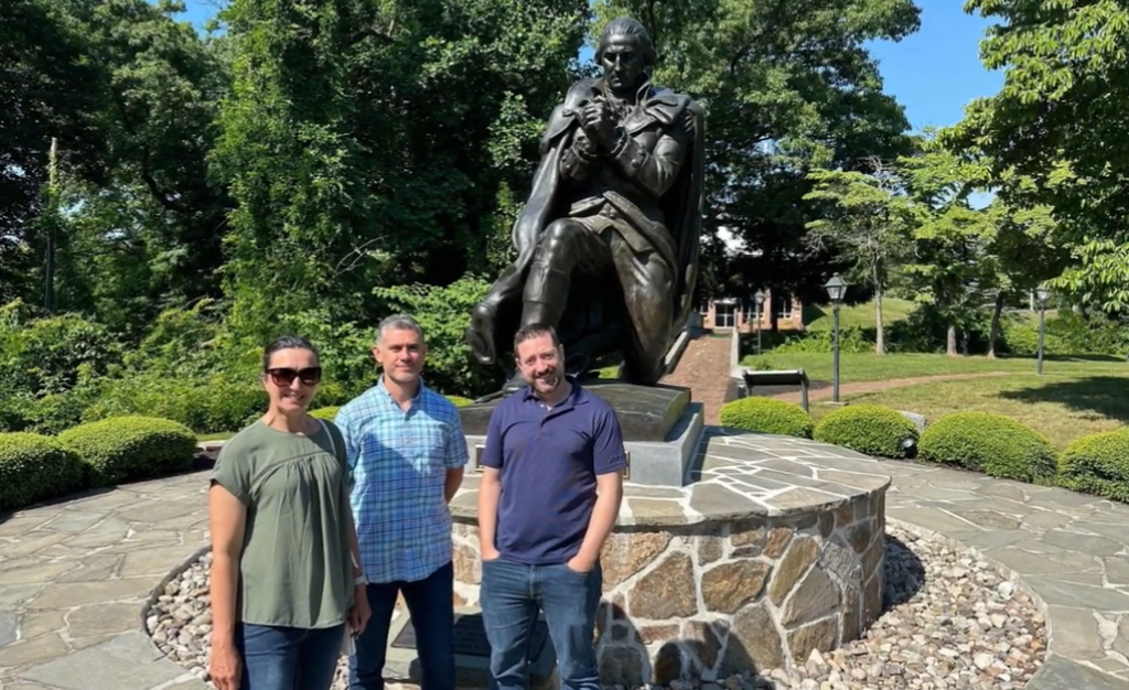 Three fellows from 2024 pose in front of a statue in a park.
