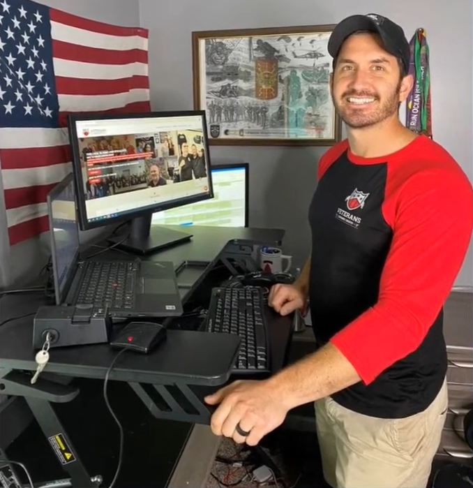 One fellow from 2024 stands at his desk with an American flag on the wall behind his computer.