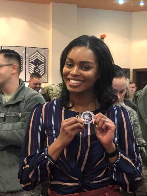 Tamara in a room of uniformed Air Force posing with a coin she received